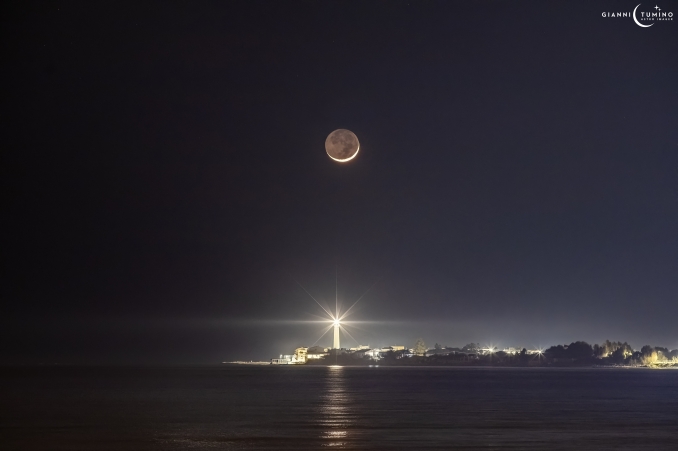 La Luna cinerea del 23 Marzo 2023 tramonta alle spalle del Faro Punta di Mola (RG) - Copyright: Gianni Tumino 