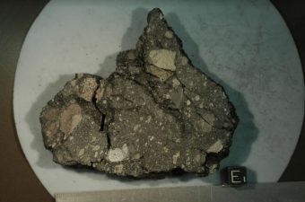 La roccia studiata da Sonia Tikoo e il suo team. Il frammento è composto da basalto e legato assieme da composti vitrei, creati dopo l’impatto di qualche asteroide. Il cubo nero in basso a destra (per scala) è di un centimetro. Crediti: Rutgers University